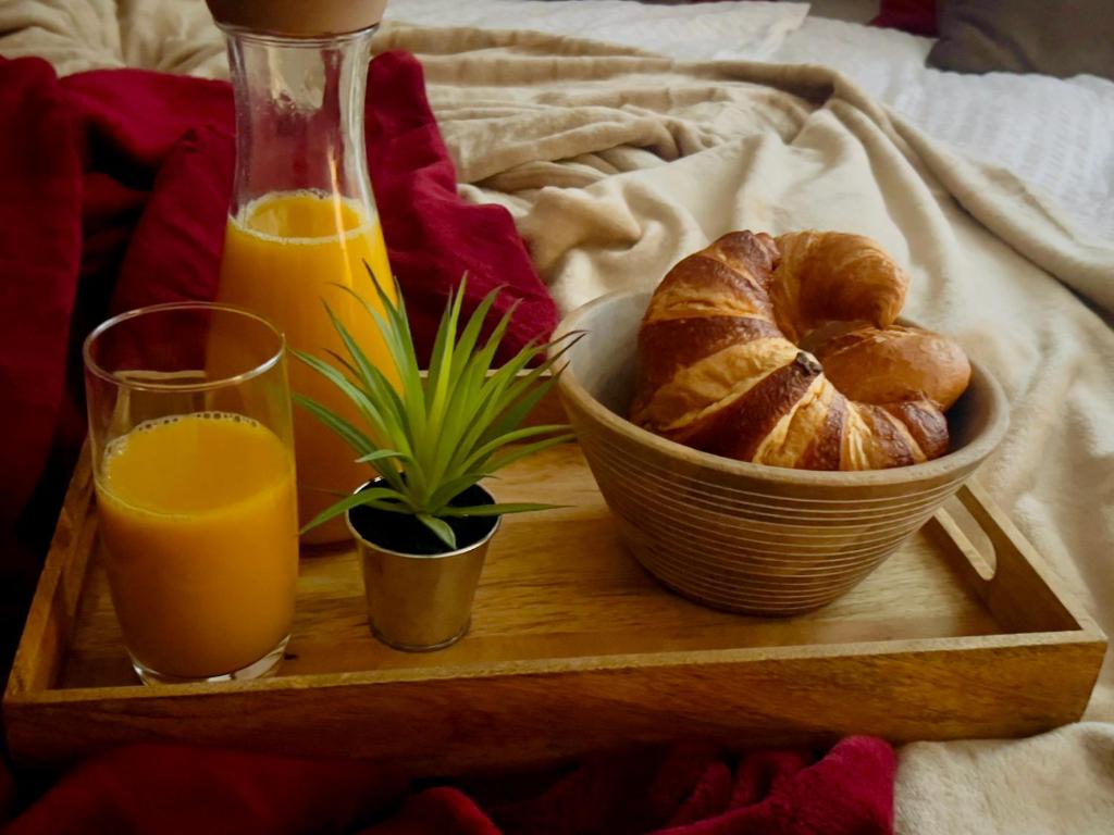 Frühstückstablett mit Croissants und Orangensaft auf dem Bett